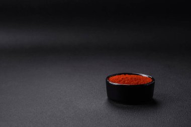 Spice smoked paprika in the form of powder in bowls and spoons on a dark concrete background. Asian cuisine ingredients