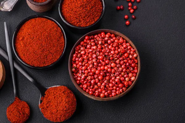 Spice smoked paprika in the form of powder in bowls and spoons on a dark concrete background. Asian cuisine ingredients