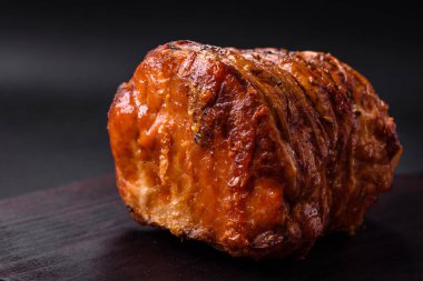 Delicious fresh smoked meat or ham with spices and herbs on a dark concrete background