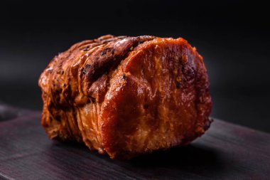 Delicious fresh smoked meat or ham with spices and herbs on a dark concrete background