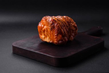 Delicious fresh smoked meat or ham with spices and herbs on a dark concrete background