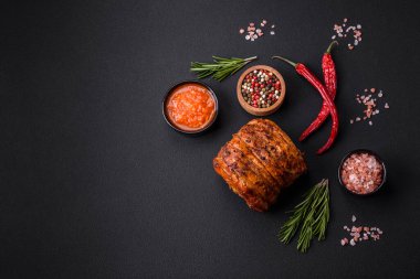 Delicious fresh smoked meat or ham with spices and herbs on a dark concrete background