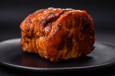 Delicious fresh smoked meat or ham with spices and herbs on a dark concrete background