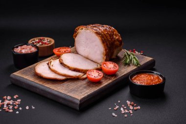Delicious fresh smoked meat or ham with spices and herbs on a dark concrete background