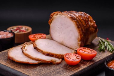 Delicious fresh smoked meat or ham with spices and herbs on a dark concrete background