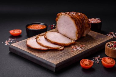 Delicious fresh smoked meat or ham with spices and herbs on a dark concrete background