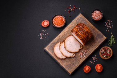 Delicious fresh smoked meat or ham with spices and herbs on a dark concrete background
