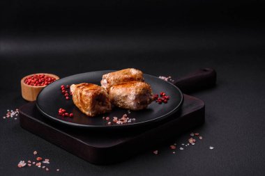 Delicious chicken or pork meat roll with mushrooms, cheese, spices and herbs on a dark concrete background