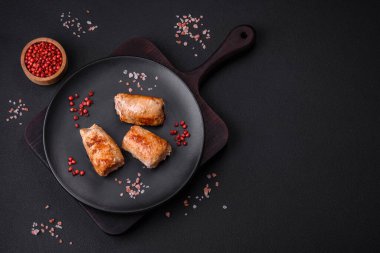 Delicious chicken or pork meat roll with mushrooms, cheese, spices and herbs on a dark concrete background