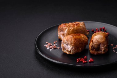 Delicious chicken or pork meat roll with mushrooms, cheese, spices and herbs on a dark concrete background