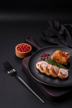 Delicious chicken or pork meat roll with mushrooms, cheese, spices and herbs on a dark concrete background