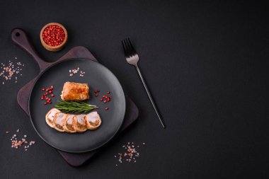 Delicious chicken or pork meat roll with mushrooms, cheese, spices and herbs on a dark concrete background