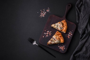 Delicious quiche with chicken, cheese, herbs, spices and herbs on a dark concrete background