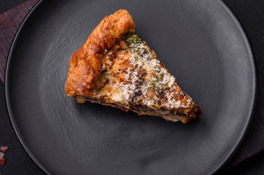 Delicious quiche with chicken, cheese, herbs, spices and herbs on a dark concrete background