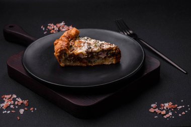 Delicious quiche with chicken, cheese, herbs, spices and herbs on a dark concrete background