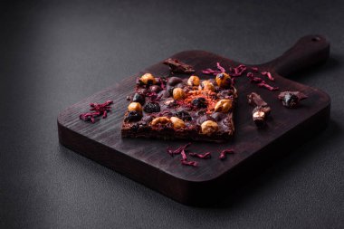 Handmade chocolate with berries, nuts and spices on a dark concrete background. Sweets made at home