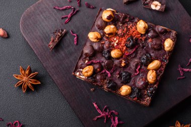 Handmade chocolate with berries, nuts and spices on a dark concrete background. Sweets made at home