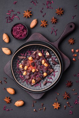 Handmade chocolate with berries, nuts and spices on a dark concrete background. Sweets made at home