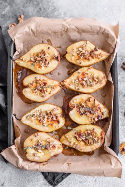 Delicious baked pear with dorblu cheese, walnut and honey on a textured concrete background. Vegetarian dish
