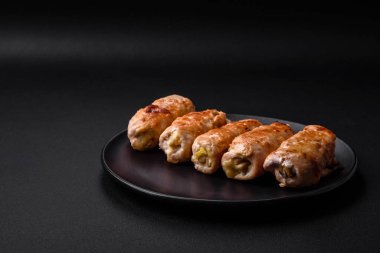 Delicious baked pork or chicken roll with mushrooms, spices and herbs inside on a dark concrete background