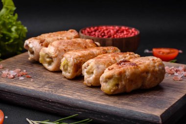 Delicious baked pork or chicken roll with mushrooms, spices and herbs inside on a dark concrete background