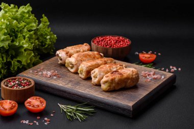 Delicious baked pork or chicken roll with mushrooms, spices and herbs inside on a dark concrete background