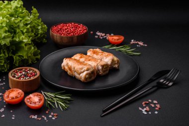 Delicious baked pork or chicken roll with mushrooms, spices and herbs inside on a dark concrete background