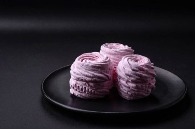 Delicious fresh natural airy marshmallows on a black ceramic plate on a dark concrete background