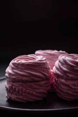 Delicious fresh natural airy marshmallows on a black ceramic plate on a dark concrete background