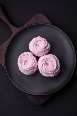 Delicious fresh natural airy marshmallows on a black ceramic plate on a dark concrete background