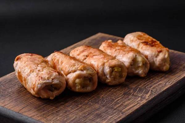 Delicious baked pork or chicken roll with mushrooms, spices and herbs inside on a dark concrete background