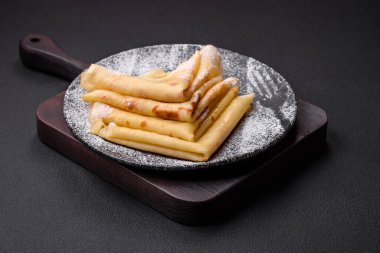Delicious fresh baked pancakes with honey and fruits on a textured concrete background. Useful healthy food