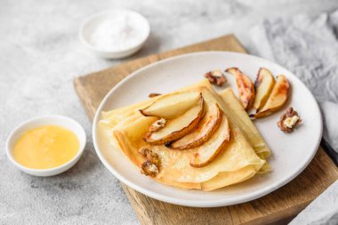 Delicious fresh baked pancakes with honey and fruits on a textured concrete background. Useful healthy food