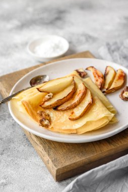 Delicious fresh baked pancakes with honey and fruits on a textured concrete background. Useful healthy food