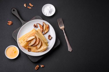 Delicious fresh baked pancakes with honey and fruits on a textured concrete background. Useful healthy food