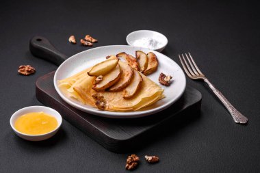 Delicious fresh baked pancakes with honey and fruits on a textured concrete background. Useful healthy food