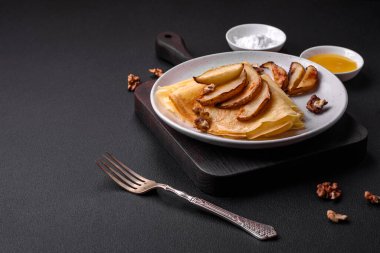Delicious fresh baked pancakes with honey and fruits on a textured concrete background. Useful healthy food
