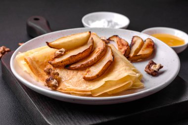 Delicious fresh baked pancakes with honey and fruits on a textured concrete background. Useful healthy food