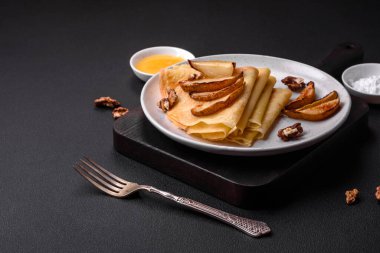 Delicious fresh baked pancakes with honey and fruits on a textured concrete background. Useful healthy food