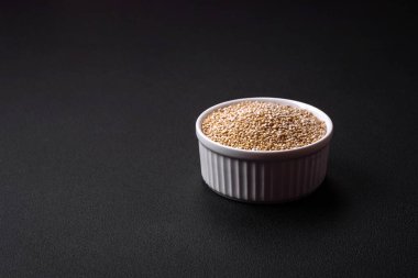 Wholesome raw quinoa in a bowl on a dark concrete background. Useful healthy food