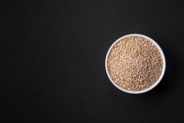 Wholesome raw quinoa in a bowl on a dark concrete background. Useful healthy food