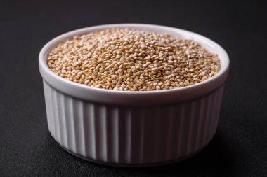 Wholesome raw quinoa in a bowl on a dark concrete background. Useful healthy food