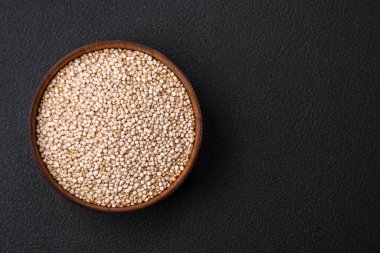 Wholesome raw quinoa in a bowl on a dark concrete background. Useful healthy food