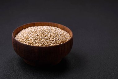 Wholesome raw quinoa in a bowl on a dark concrete background. Useful healthy food