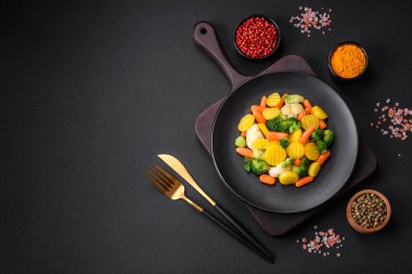Delicious fresh vegetables steamed carrots, broccoli, cauliflower on a black plate on a dark concrete background