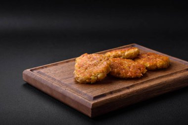 Delicious hearty vegetarian or vegan dish in the form of cutlets or patties consisting of potatoes, carrots, onions and beans on a dark concrete background