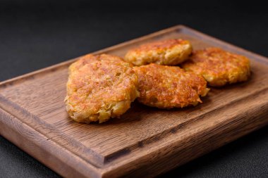 Delicious hearty vegetarian or vegan dish in the form of cutlets or patties consisting of potatoes, carrots, onions and beans on a dark concrete background