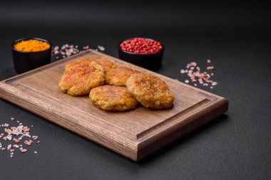 Delicious hearty vegetarian or vegan dish in the form of cutlets or patties consisting of potatoes, carrots, onions and beans on a dark concrete background