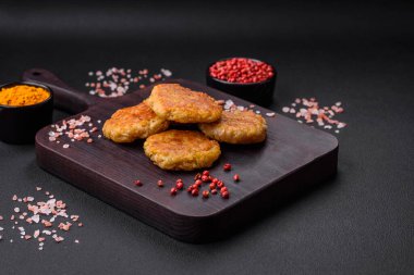 Delicious hearty vegetarian or vegan dish in the form of cutlets or patties consisting of potatoes, carrots, onions and beans on a dark concrete background