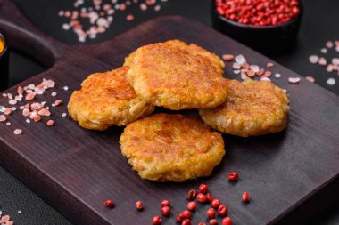 Delicious hearty vegetarian or vegan dish in the form of cutlets or patties consisting of potatoes, carrots, onions and beans on a dark concrete background